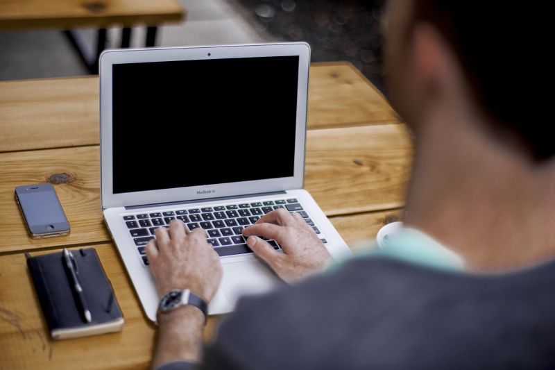 Stock photo of man typing on a Mac laptop