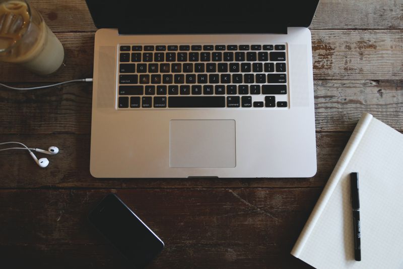 Stock Photo of a Mac laptop, a cup of coffee, and an iphone on a wood table